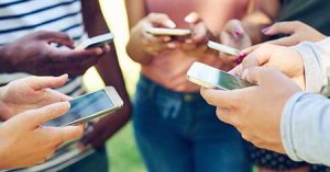 teens holding iphones out and texting in a circle