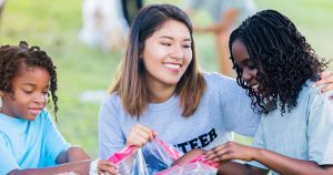 Three young multi-ethnic girls helping clean up trash from a park