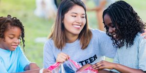 Three young multi-ethnic girls helping clean up trash from a park